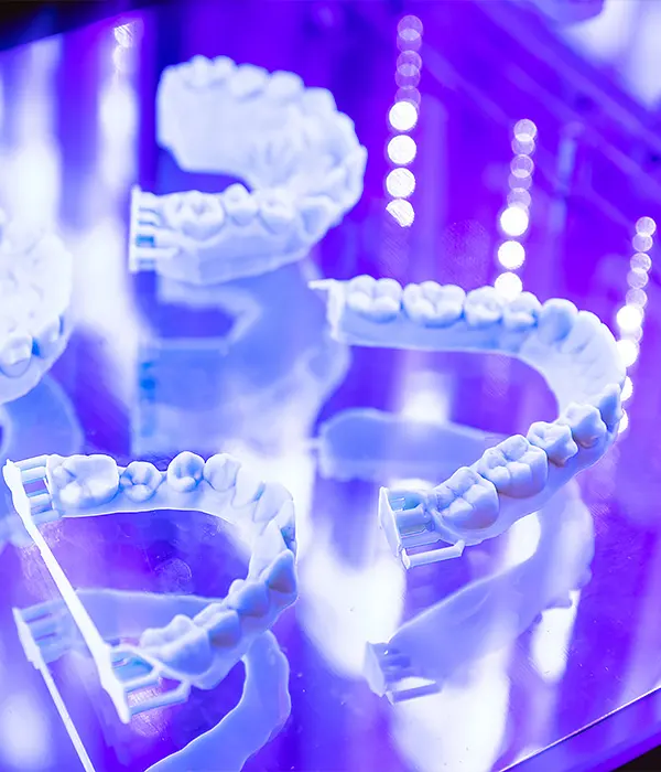Close-up of 3D printed dental models curing under blue UV light, showcasing advanced digital dentistry technology.