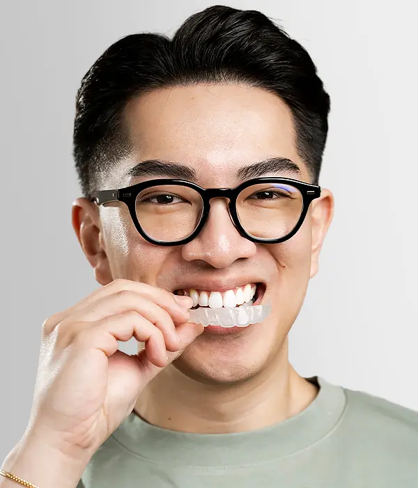 Person placing clear aligner on teeth for orthodontic treatment