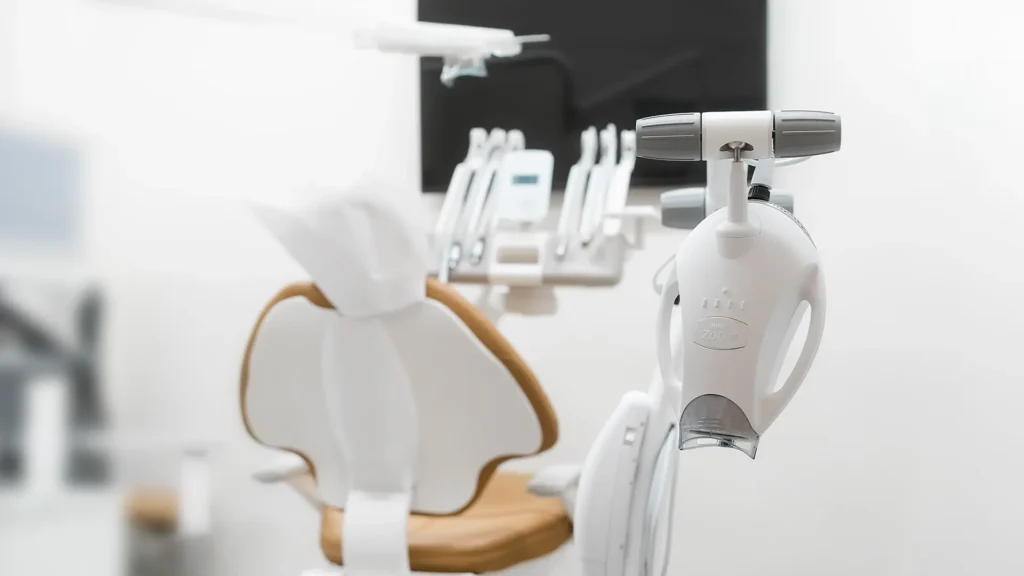 Close-up of a Philips Zoom LED teeth whitening machine in a bright, modern dental treatment room with a white and tan dental chair in the background.
