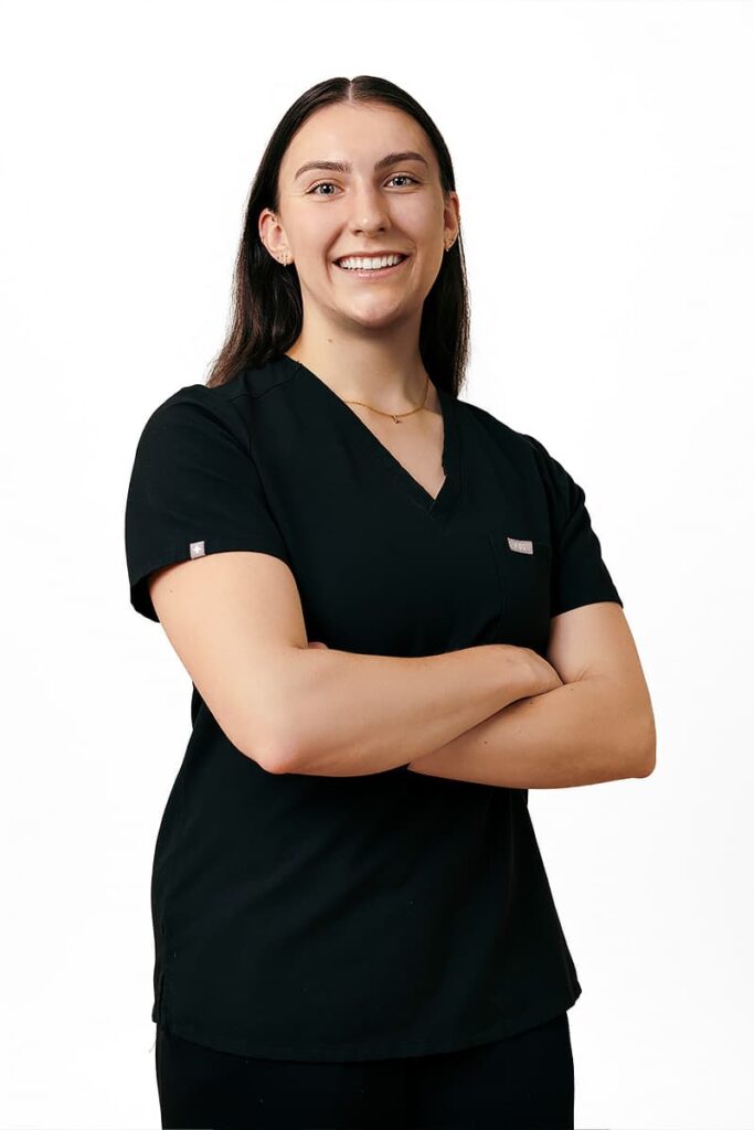 Dr. Olivia Gables, general dentist at Landmark Dental in Regina, smiling in black scrubs with arms crossed